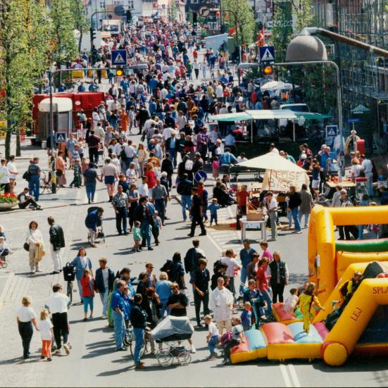 Farvefoto af Ahlgade i 1995 med hoppeborg og mange deltagere til Børnehjælpsdagen.