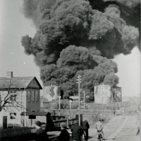 Sort-hvid foto: Røgsky stiger op fra brændende siloer.