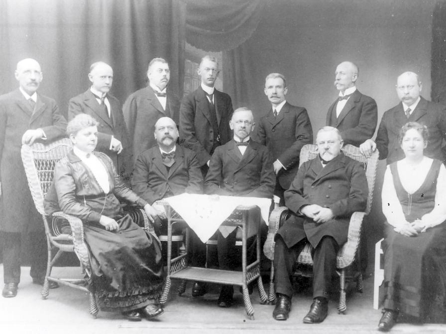 Sort-hvid foto af 12 personer i jakkesæt og kjoler.